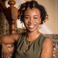 Alma therapist Rode Toussaint leaning up against a polished wood bannister in a light-dappled, homey room.