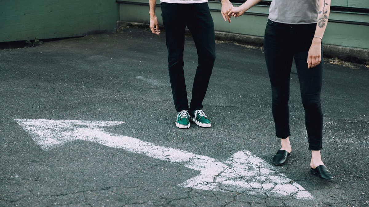 Man and woman holding hands on a blacktop street.