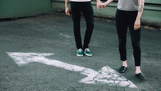 Man and woman holding hands on a blacktop street.