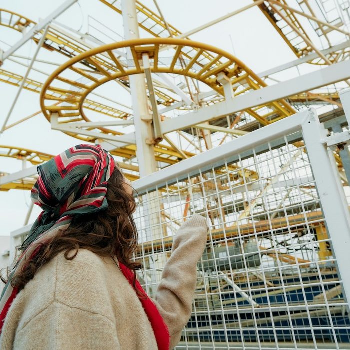 A woman in a colorful head scarf pointing at a rollercoaster