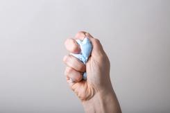 A light-skinned hand squeezing some kind of blue stress ball or putty.