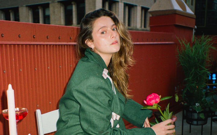 author Haley Jakobson sits on a rooftop at night holding a red rose