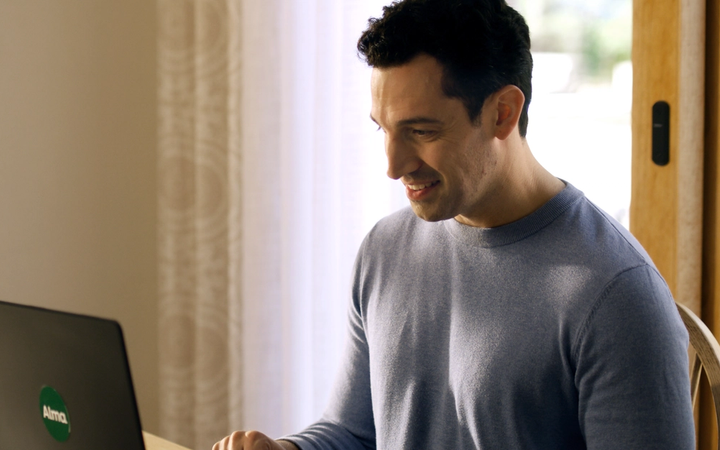 Man in blue shirt in front of laptop