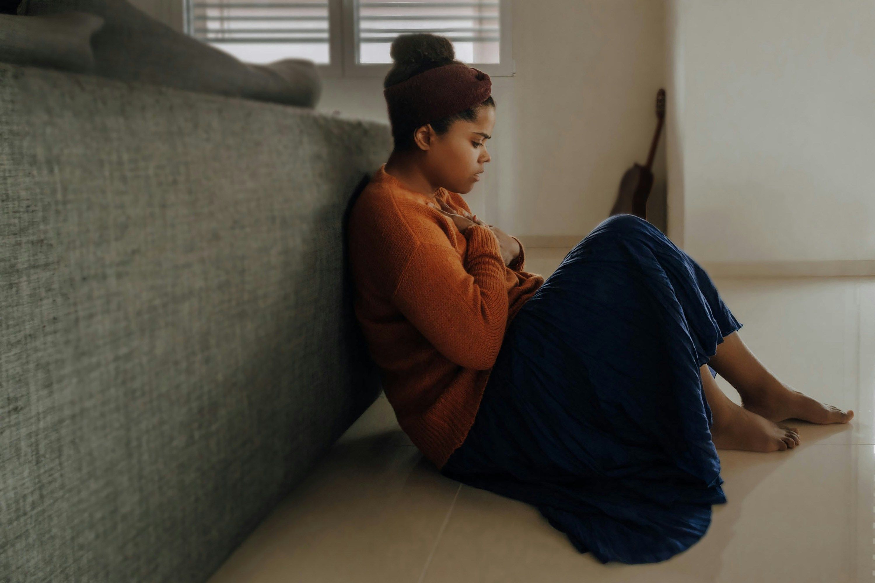 Woman in orange sweater sitting on the floor