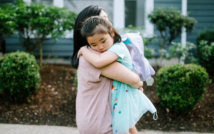 Mother holds sleeping daughter in her arms on a walking path