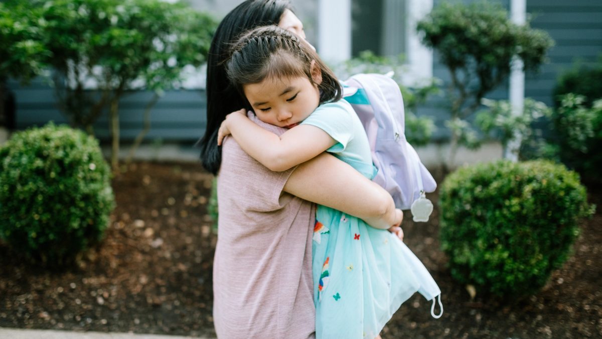 Mother holds sleeping daughter in her arms on a walking path