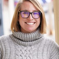 Alma therapist Meagan Faraone smiling to camera in a grey knit sweater.