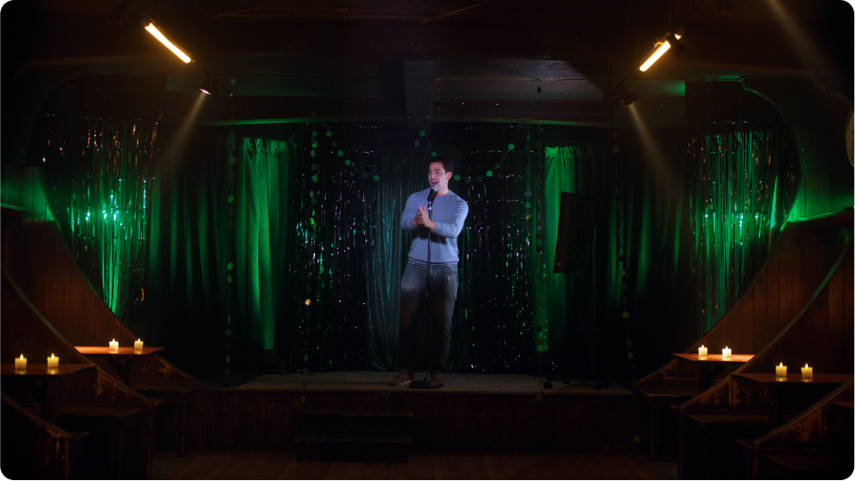 Man in a blue shirt alone on a stage singing karaoke in an empty bar