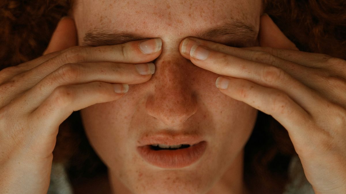 A woman with chronic pain rubbing her eyes