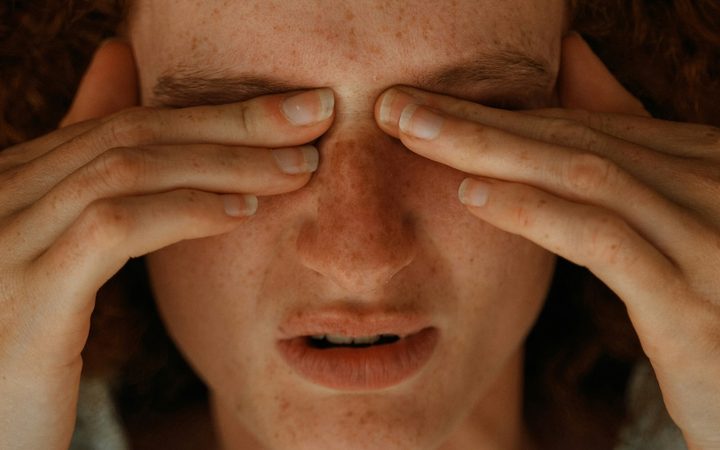A woman with chronic pain rubbing her eyes