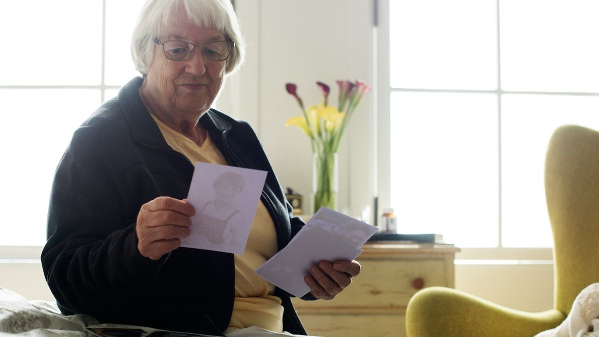 An older woman looks at photographs from her past in a reminiscence therapy session