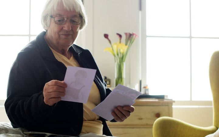 An older woman looks at photographs from her past in a reminiscence therapy session