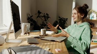 A teenager bathed in sunlight from the window, talking animatedly with her virtual therapist at her computer.