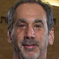 A cropped photo showing a neutral Dr. Mark Serper, gazing to the camera, wearing a suite.