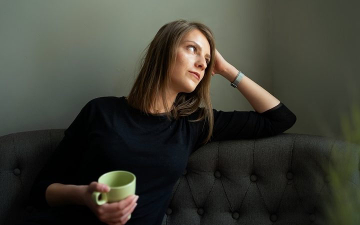 A woman sitting on a green couch looks deflated after her first therapy session.
