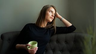 A woman sitting on a green couch looks deflated after her first therapy session.