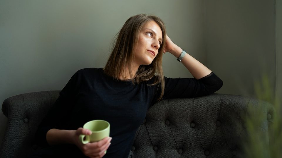 A woman sitting on a green couch looks deflated after her first therapy session.
