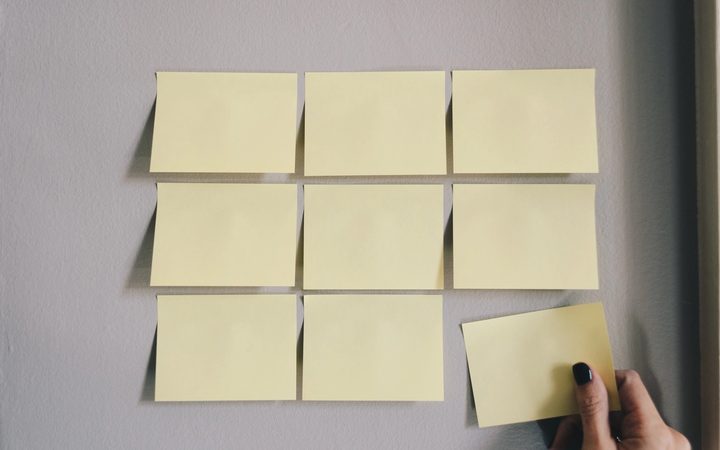 A person places sticky notes on their wall to visualize and plan their work as a coping strategy for ADHD.