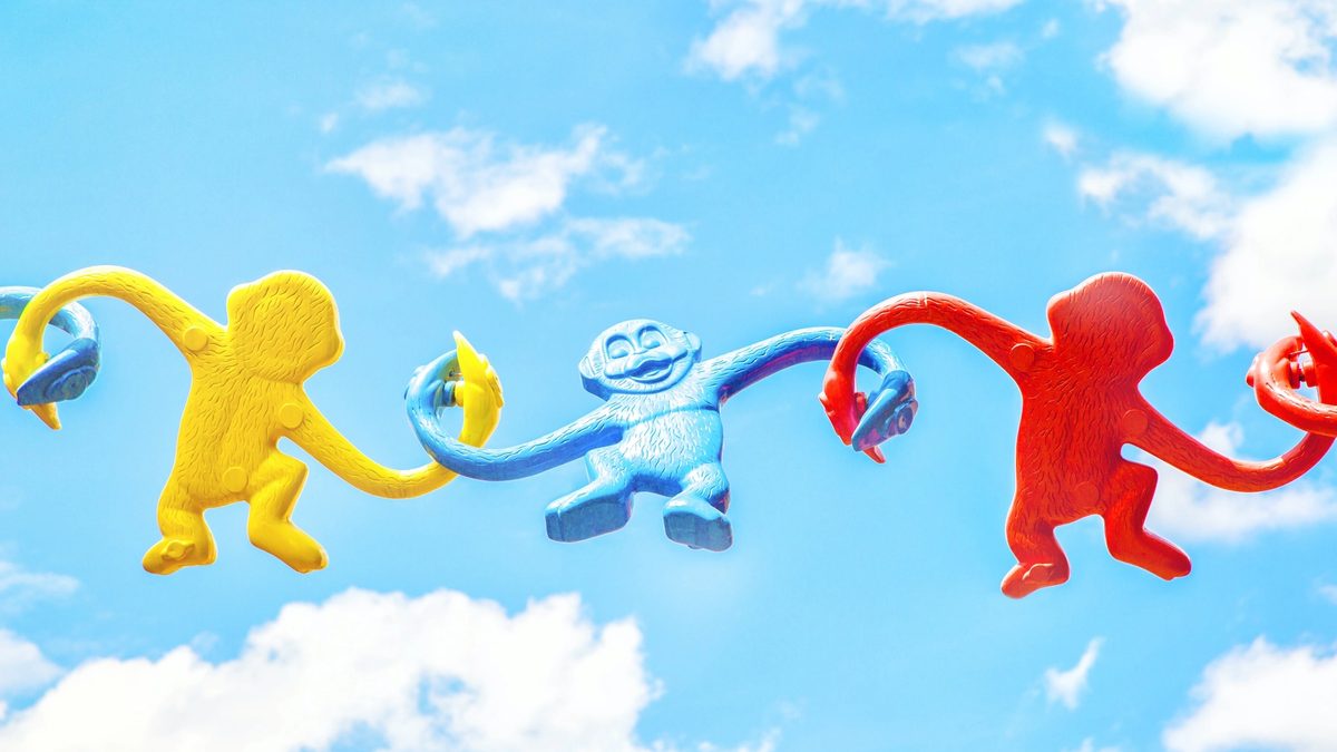Three different monkey-in-a-barrel figurines, tenuously linked up against the backdrop of a sunny sky, showing the importance of community and a three-pronged approach to fighting stigma.