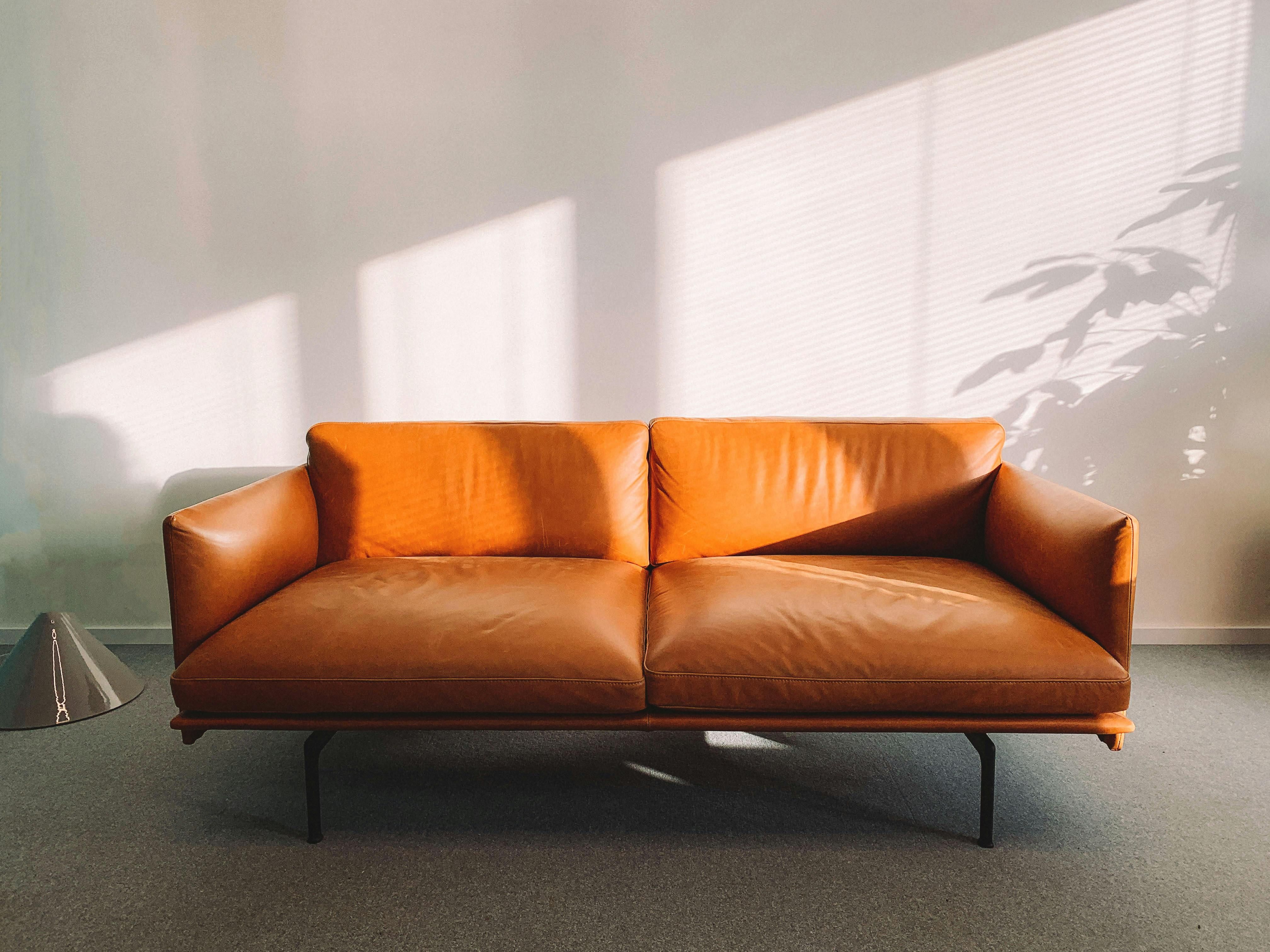 A cognac-colored leather couch, bathed in sunlight shining through the window of a trauma therapist's office.
