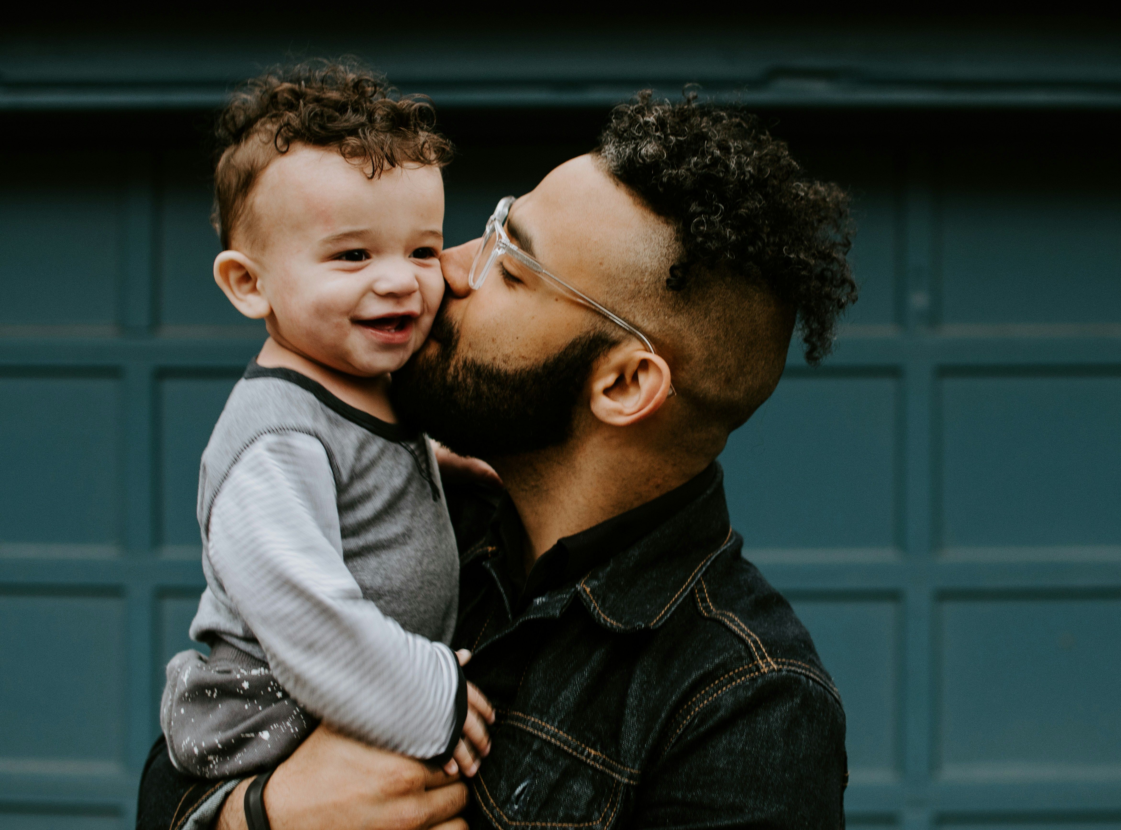 Father in jean shirt holding his baby boy with matching haircut