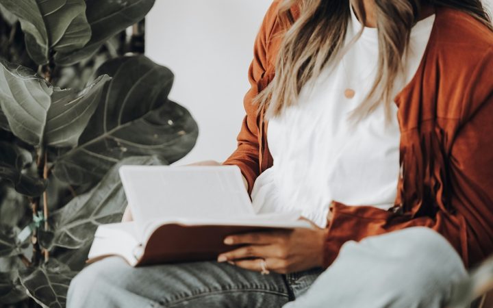 A casually dressed woman sits with a bible on her lap in a therapist's office