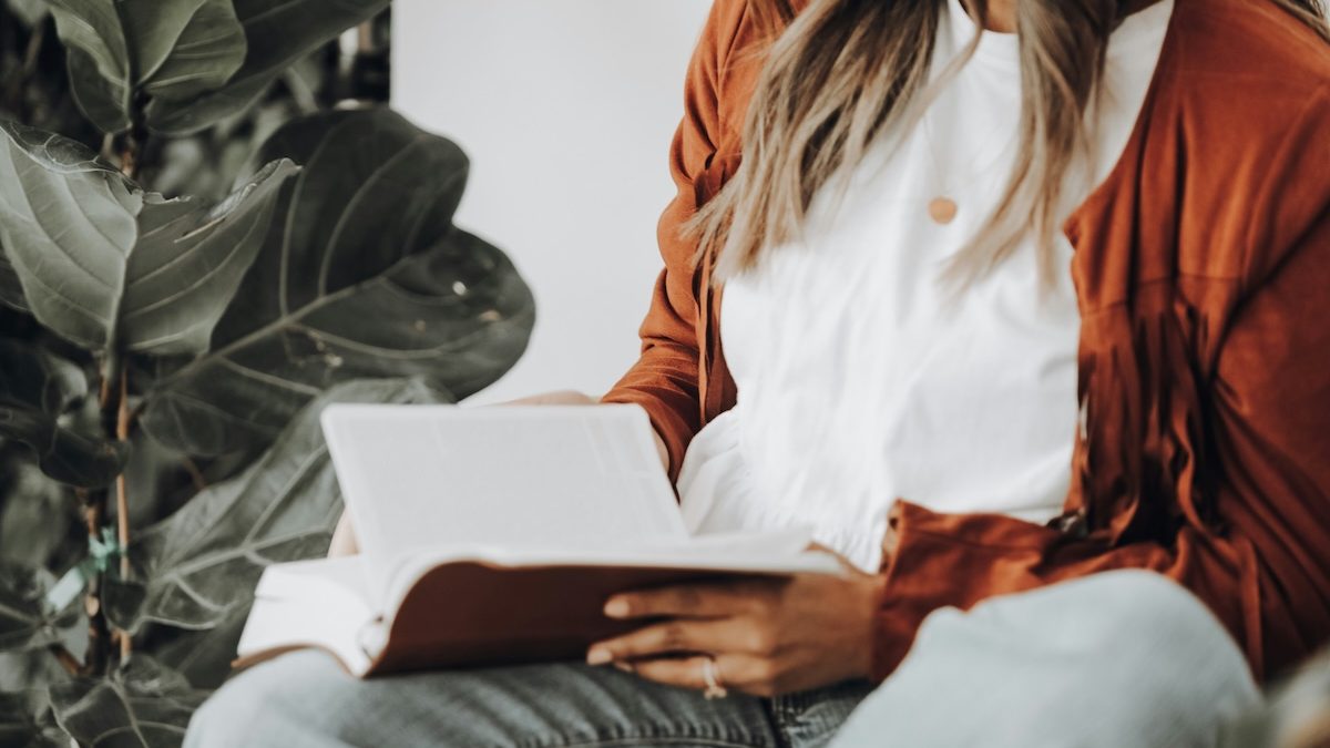 A casually dressed woman sits with a bible on her lap in a therapist's office