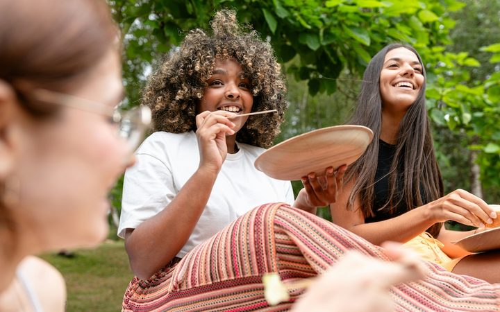 a woman eating with friends in the park