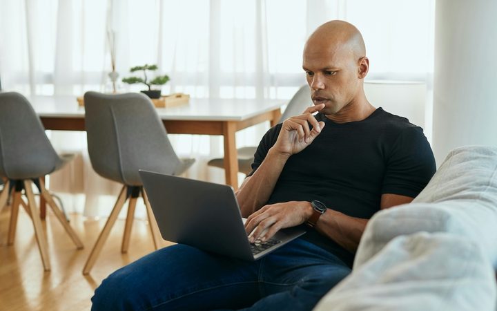 A man is at home on his laptop, learning about Optum's EAP