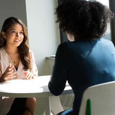 A young Asian American social work student speaks with her mentor.