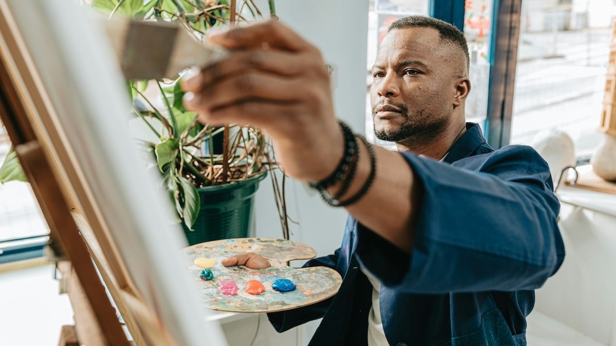 a man paints creatively on a canvas in his home studio