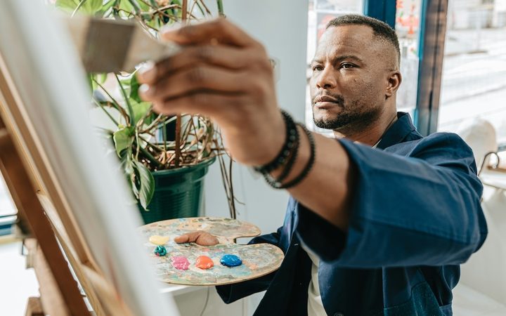 a man paints creatively on a canvas in his home studio