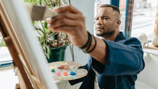 a man paints creatively on a canvas in his home studio
