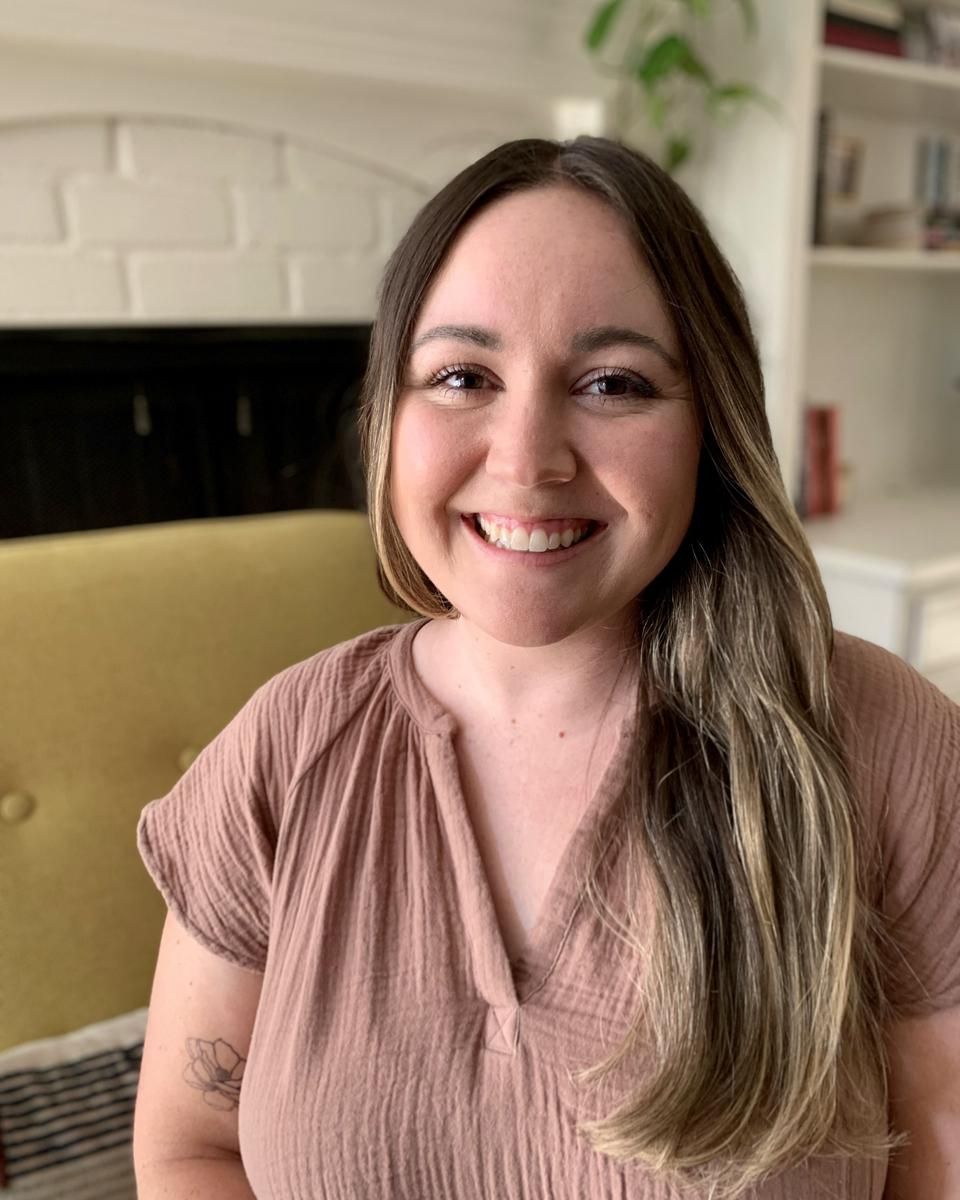 Lucy, a therapist with long brown hair, smiling from her well-designed home office.