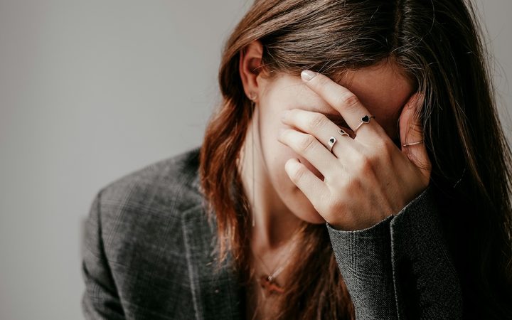 A woman in a therapy session covers her face as she prepares to share something embarrassing