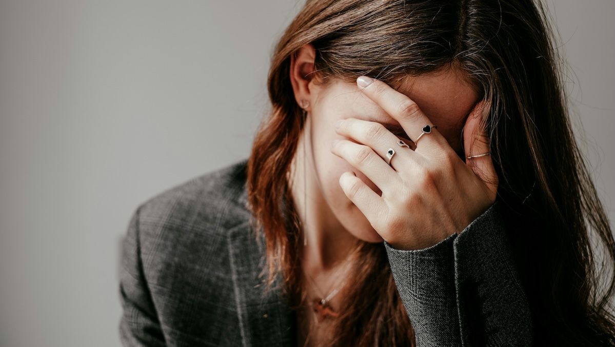 A woman in a therapy session covers her face as she prepares to share something embarrassing