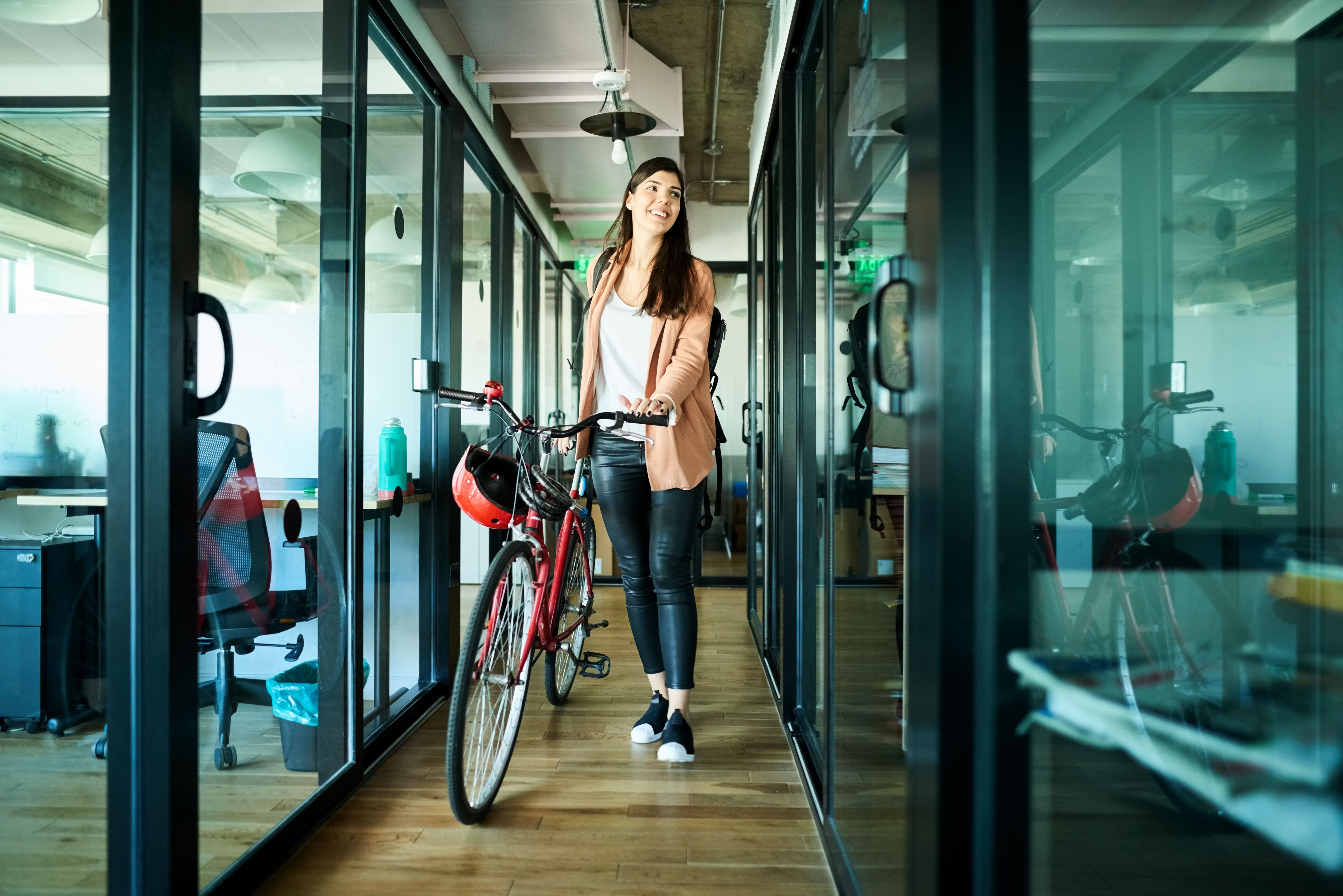 Woman walking into an office with her bicycle.