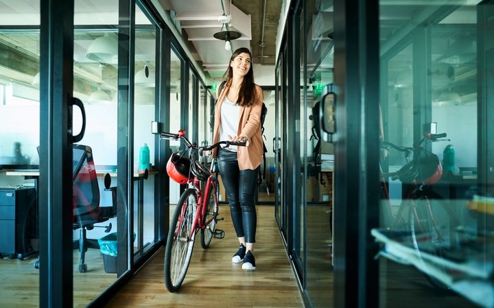 Woman walking into an office with her bicycle.
