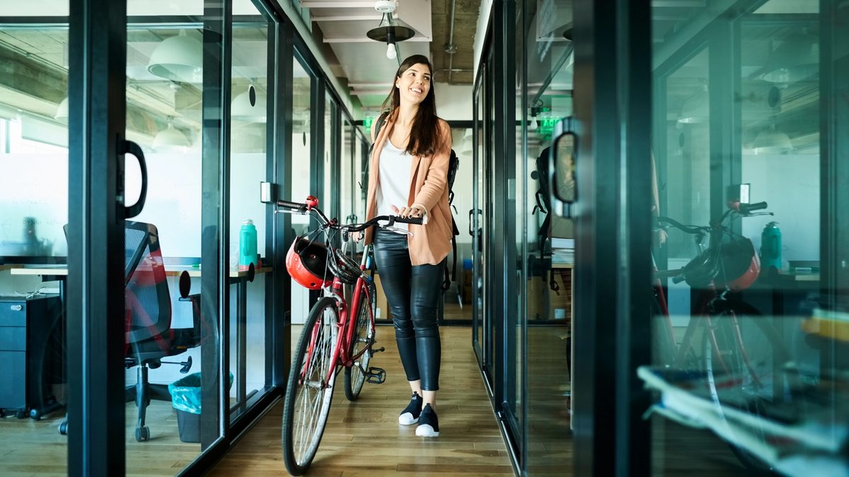 Woman walking into an office with her bicycle.