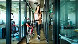 Woman walking into an office with her bicycle.