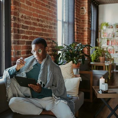 Person with glasses on a couch holding a tablet.