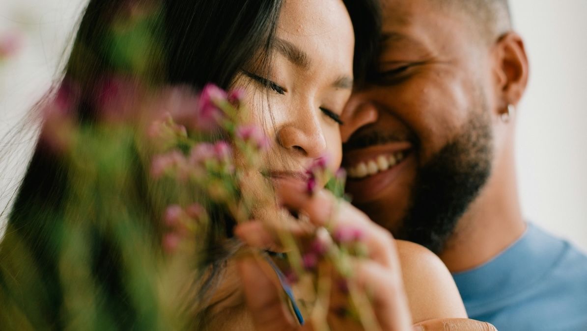 A couple stands facing each other in front of a glass sliding door having an in-depth conversation.