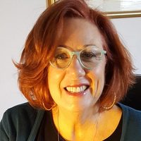 Janet Anselmo-Henson, LPC, smiling to the camera in her therapy office.