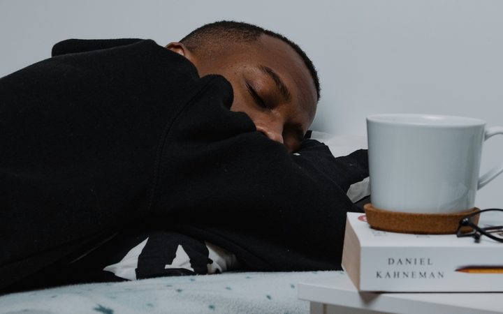 a young man slumps on his desk after losing an hour of sleep due to daylight saving time