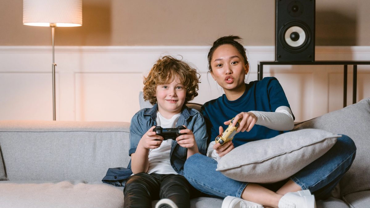 A therapist bonding a child she supports, playing a video game side-by-side.