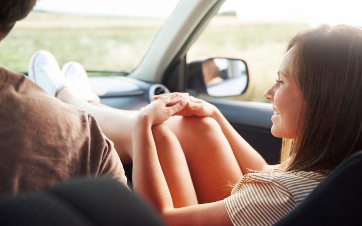 A couples in the car listening to podcasts on a road trip