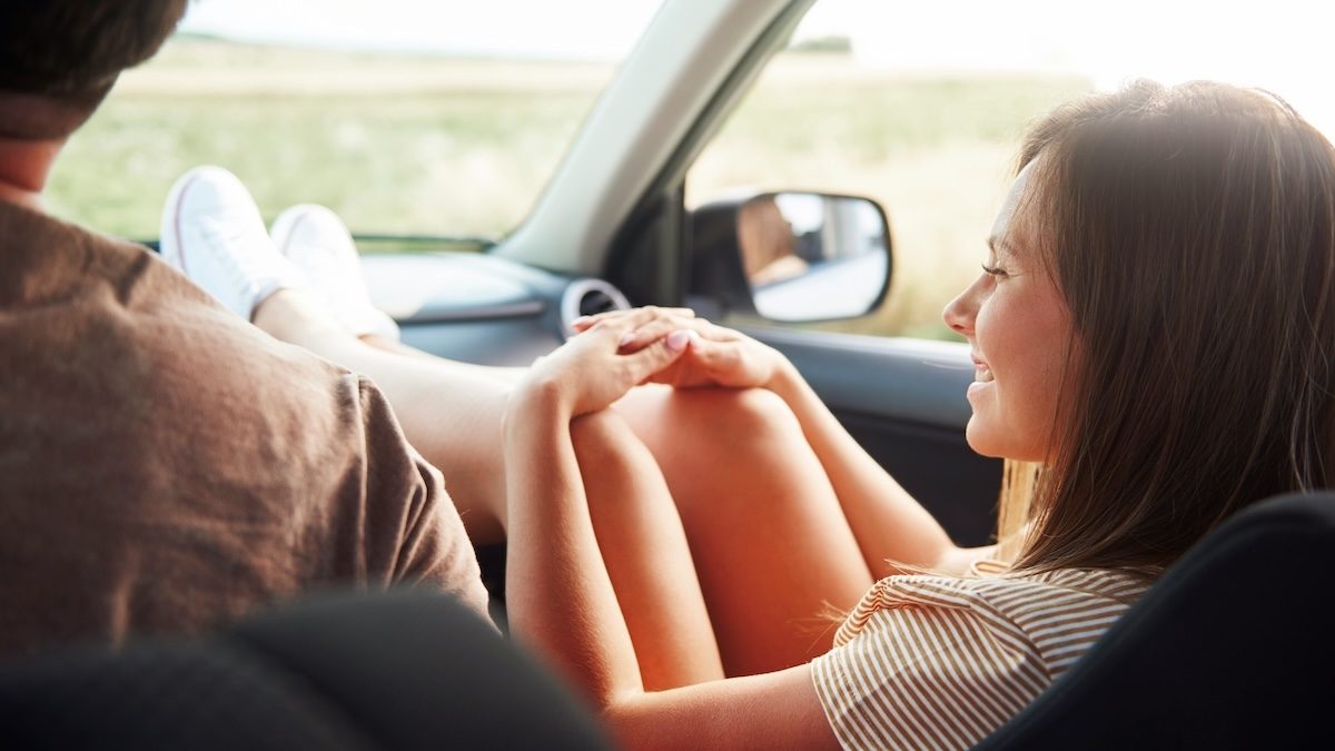 A couples in the car listening to podcasts on a road trip