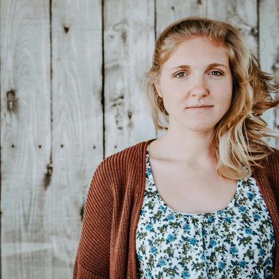 An emotionally exhausted therapist steps outside for fresh air, a rugged fence behind her.