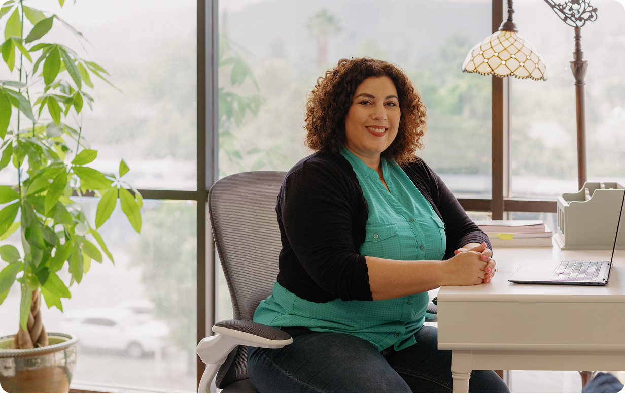 A provider sitting at their desk, smiling at the camera