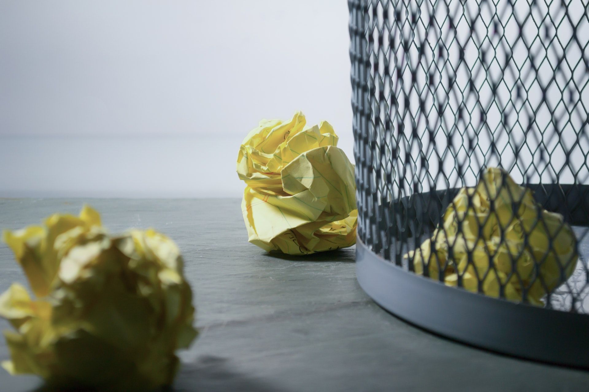 Rejected ideas, shown as crumpled pieces of paper aimed for the trash bin.